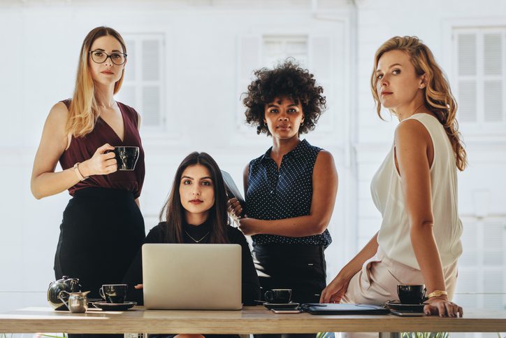 A group of women standing around a table.