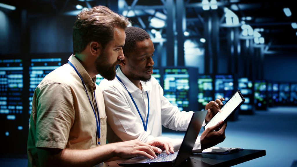 Two professionals collaborating over a tablet in a high-tech environment.