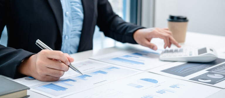 Person analyzing business charts and graphs on paper.