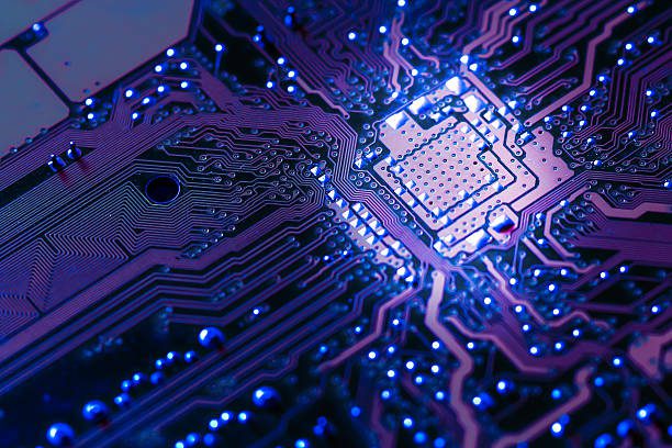 Close-up of an illuminated electronic circuit board with vibrant blue and purple lighting.